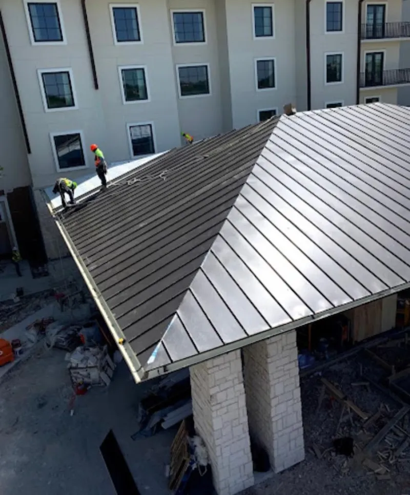 Crew installing standing seam metal roof panels on a commercial project in Roxboro